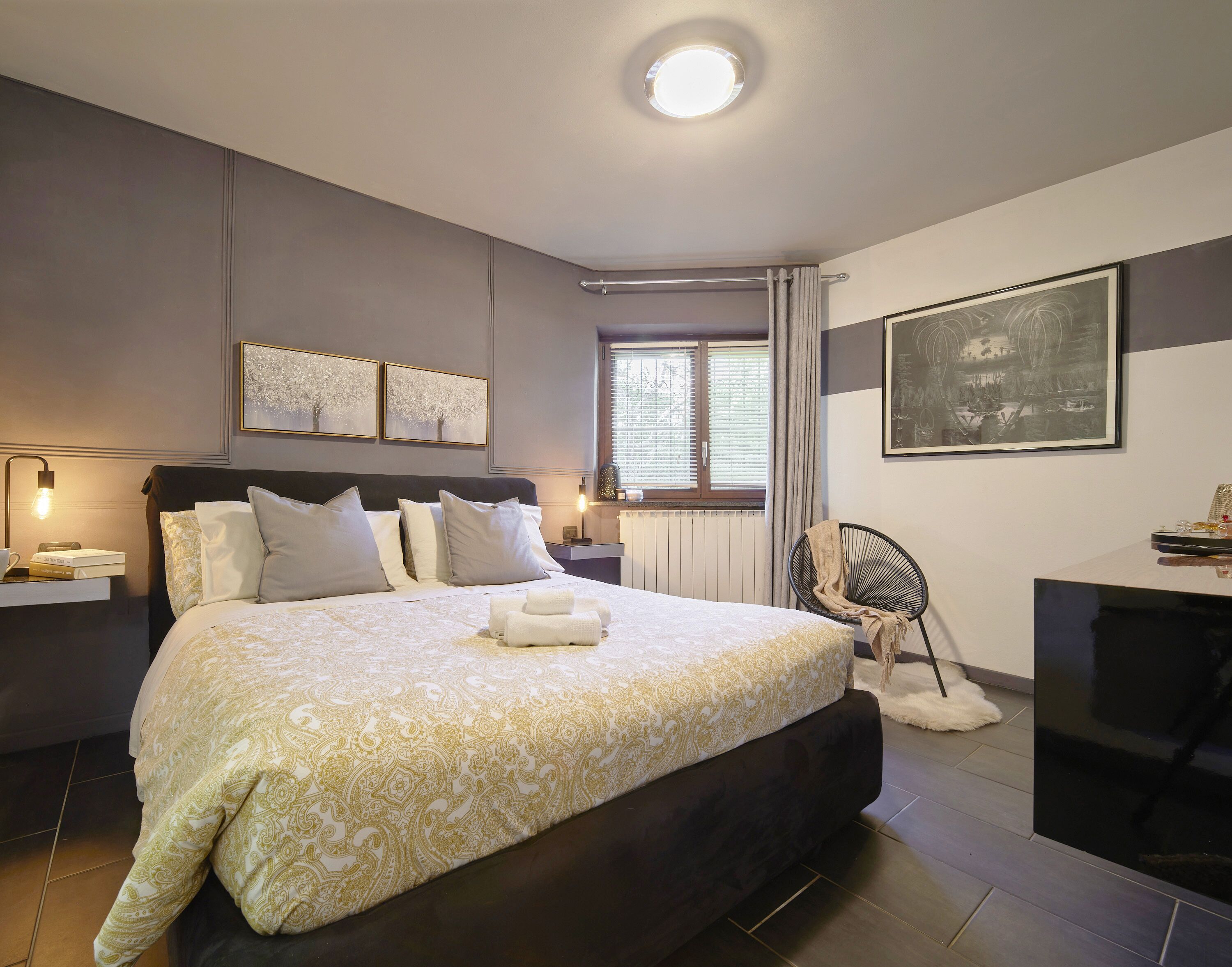 Ein modernes Schlafzimmer mit einem großen Bett, Nachttischen, einem Schreibtisch und einem Sessel.