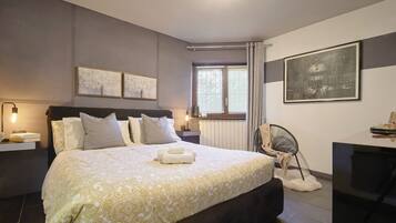 Ein modernes Schlafzimmer mit einem großen Bett, Nachttischen, einem Schreibtisch und einem Sessel.