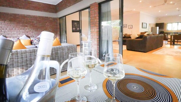 Un salon moderne avec un mur en briques, un ensemble de canapés et un coin repas avec une table mise pour le repas.