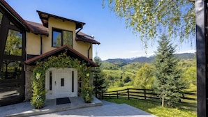A two-story house with a white door, a stone foundation, and a wooden fence.