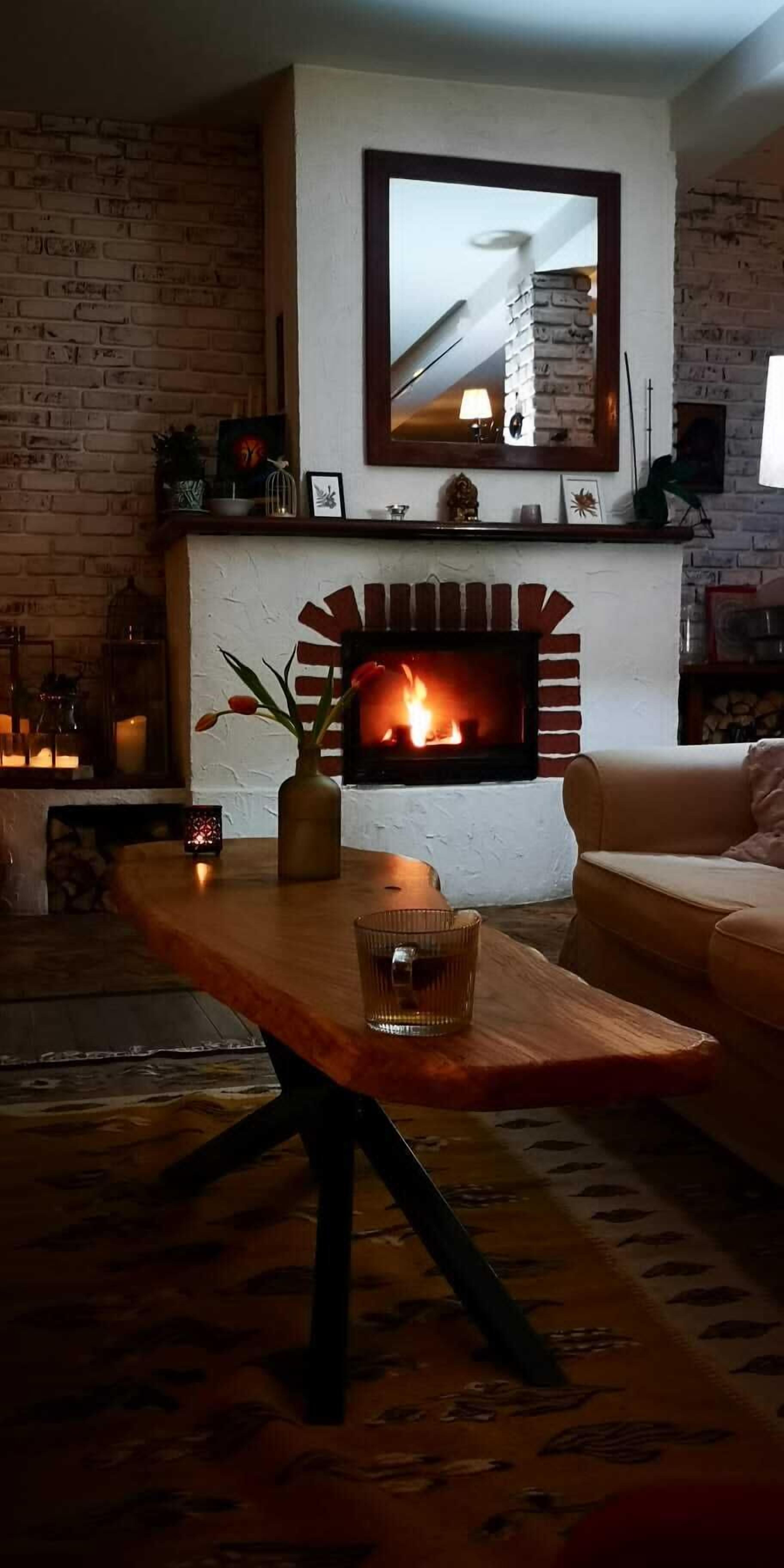 Una sala acogedora con chimenea de ladrillo, una mesa de centro de madera y un sofá.
