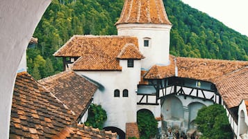Un edificio histórico con una torre destacada, rodeado de arquitectura tradicional y abundante vegetación.