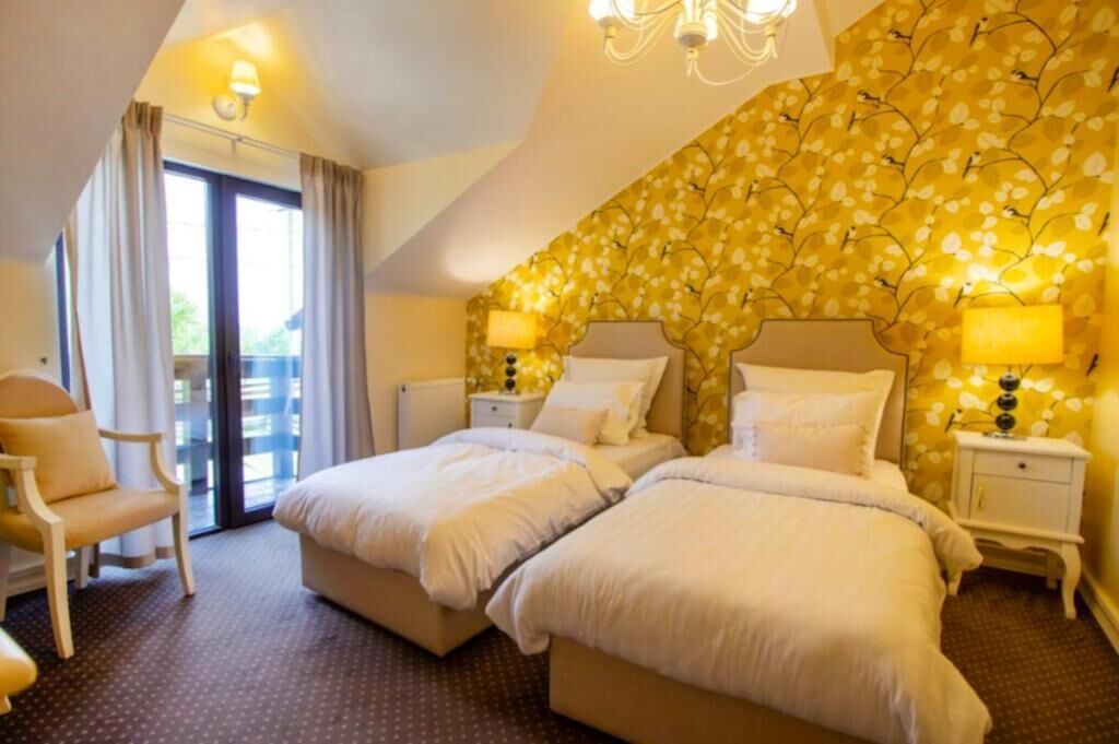 Een hotelkamer met twee bedden, een stoel, een balkon en een behang met een patroon.