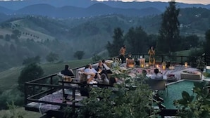 A terrace with a pool, surrounded by greenery and mountains.