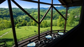 A terrace with a view of a green valley and mountains.
