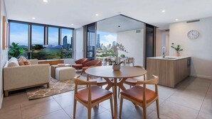 Un salon moderne avec un coin repas, de grandes fenêtres et une vue sur le paysage urbain.