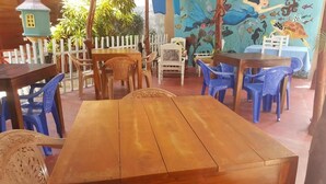 A restaurant with wooden tables and blue plastic chairs. - Canoe Beach Resort (Tangalle)