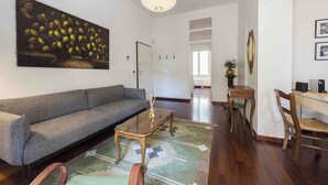 A living room with a sofa, coffee table, and a painting on the wall. - Poliziano Apartment by Mmega (Florence)