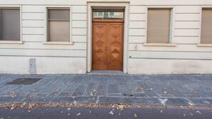 A building facade with a double wooden door, a small window above the door, and a number '21' on the right side. - Poliziano Apartment by Mmega (Florence)