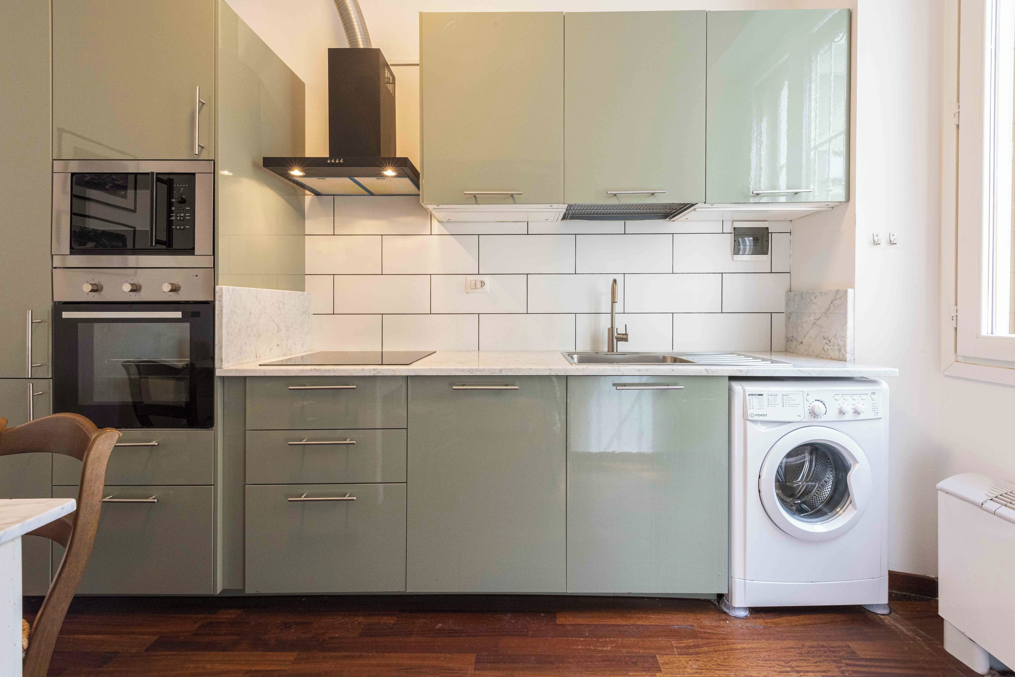 A modern kitchen with built-in appliances, a dishwasher, and a washing machine.