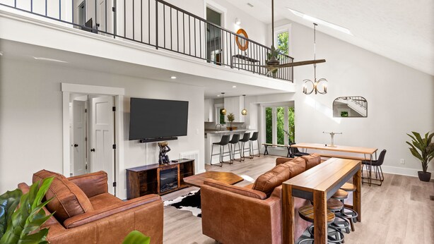 A spacious living area with a high ceiling, a dining area, and a kitchen. - Cape Fear Treehouse Boat Ramp, Dock, Kayaks, Firepit, Games (Pender County)