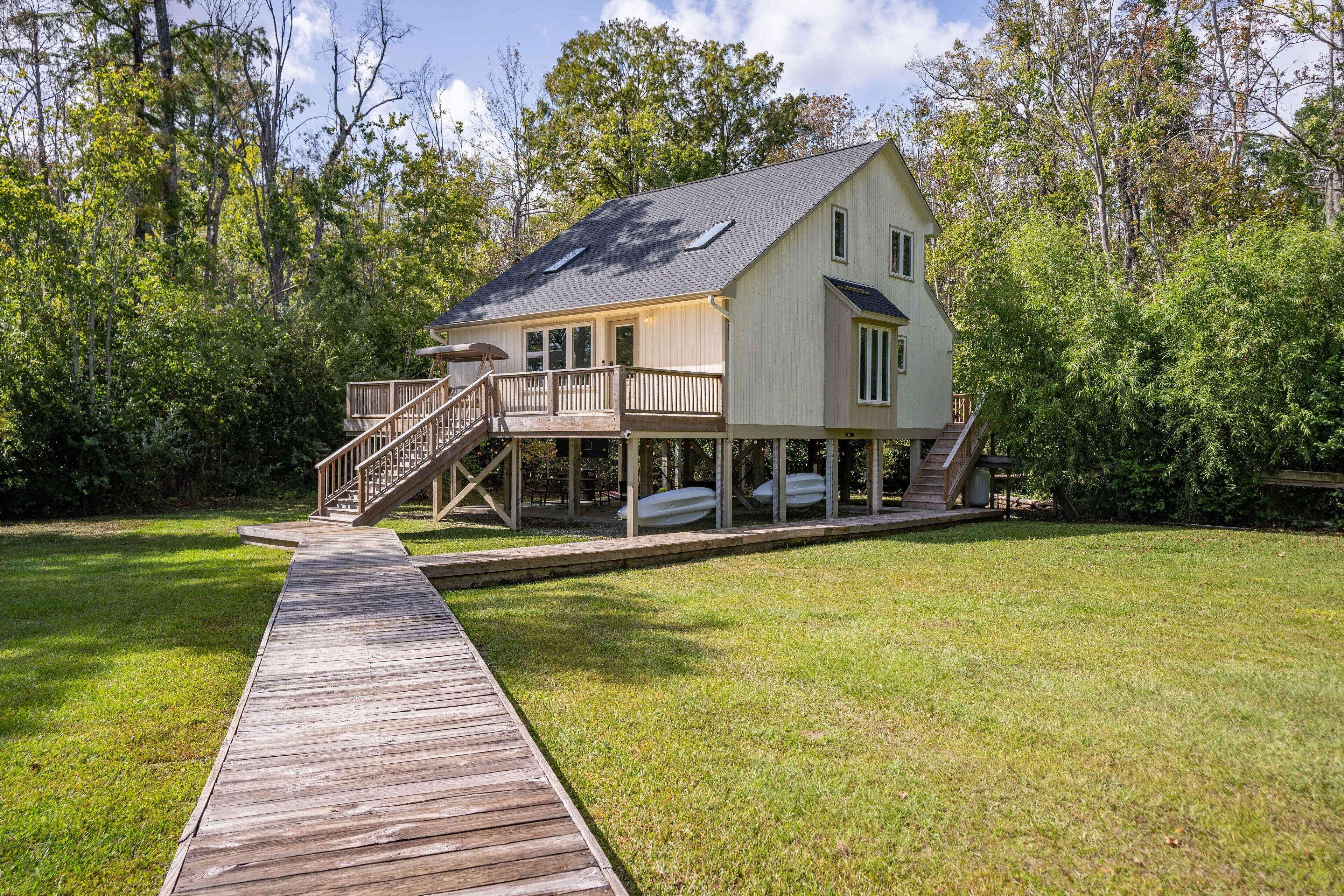 A two-story house with a wooden deck leading to a covered porch.