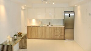 A modern kitchen with white cabinets, a stainless steel refrigerator, and a wooden countertop. - Lux design 2 bedroom unit sleeps 6 in SoBe best area (Miami Beach)