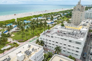 A hotel with a rooftop pool, a beach view, and a parking area. - Luxury Large 1-Bedroom at Carlyle South Beach (Miami Beach)