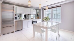 A modern kitchen with stainless steel appliances, white cabinetry, and pendant lighting.