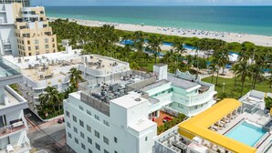 A hotel with multiple buildings, a rooftop pool, and a beach view.