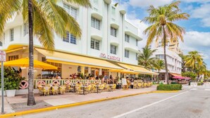 A building with a 'Carlisle' sign, outdoor seating, palm trees, and a clear sky.