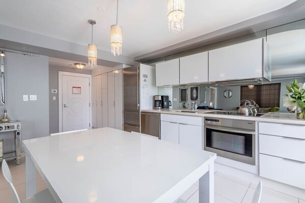 A modern kitchen with white cabinetry, stainless steel appliances, and pendant lighting. - Luxury Large 1-Bedroom at Carlyle South Beach (Miami Beach)