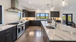 Una cocina moderna con armarios oscuros, una isla grande e iluminación colgante.
