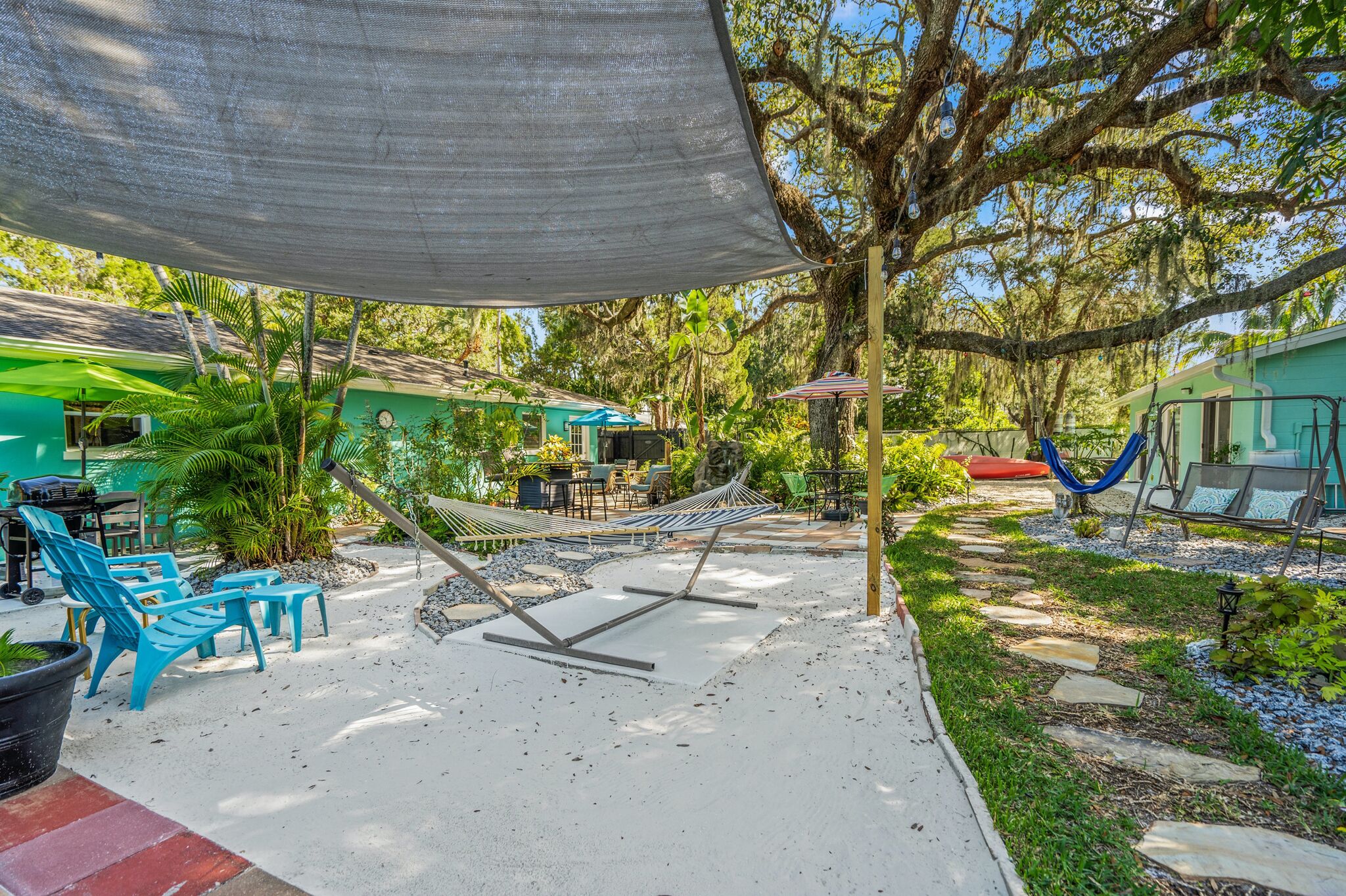 A patio area with outdoor seating, a hammock, and a shaded area.