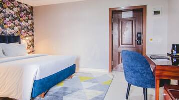 Une chambre d’hôtel comprenant un lit, un bureau avec une chaise, une lampe de bureau, une machine à café et un téléviseur.