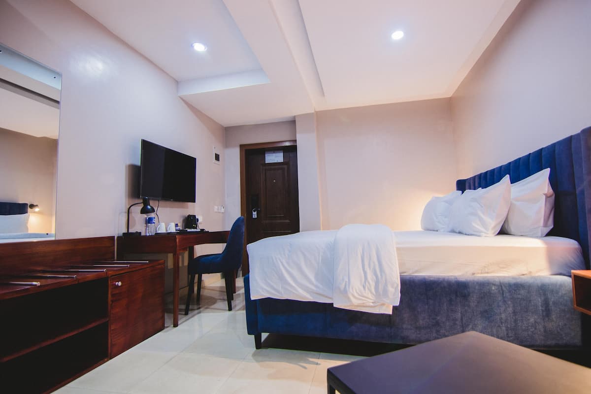A hotel room with a bed, desk, chair, and a television.