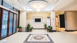 A hotel lobby with a chandelier, seating area, and a large window. - White Stones Hotel (Port Harcourt)