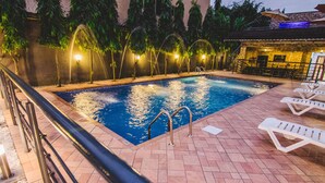 A swimming pool with a tiled deck, a metal railing, and a few lounge chairs. - White Stones Hotel (Port Harcourt)