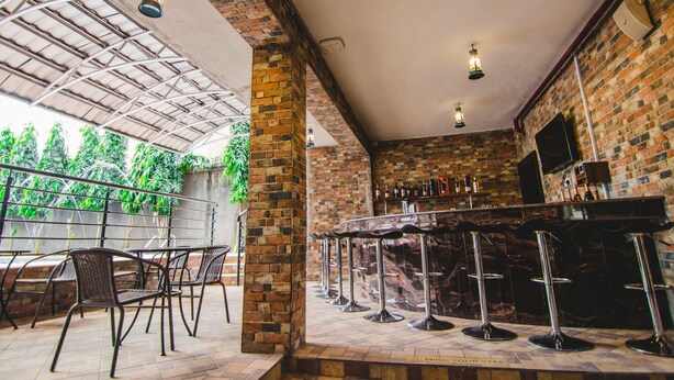 A bar area with brick walls, a bar counter, and multiple stools. - White Stones Hotel (Port Harcourt)