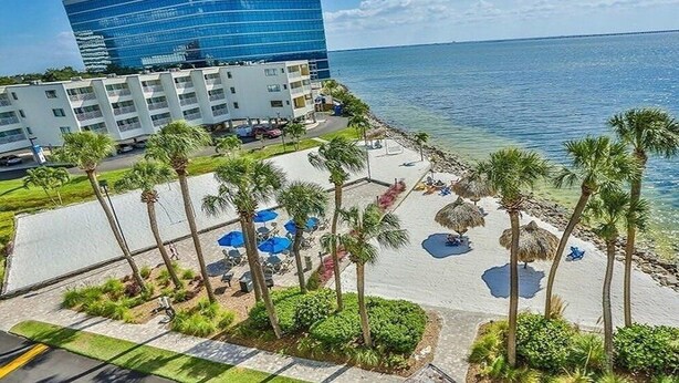 A beachfront hotel with a modern building, a pool area with umbrellas, and palm trees. - TAMPA CONDO (Tampa)