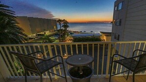 A balcony with two chairs and a small table, overlooking a body of water and buildings. - TAMPA CONDO (Tampa)