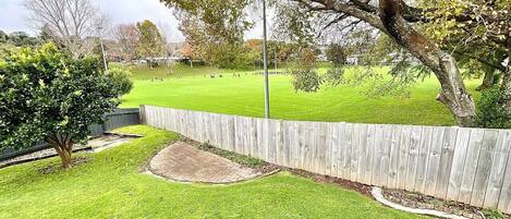 A well-maintained backyard with a wooden fence, a small tree, and a grassy lawn.
