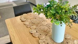 En matplats med ett träbord, en vävd bordsduk och en krukväxt.