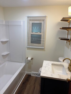 Kylpyhuone, jossa on kylpyamme, wc, pesuallas ja ikkuna, jossa on sälekaihtimet.