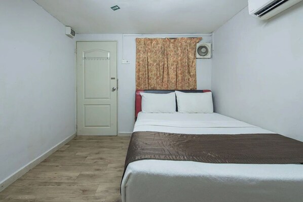 Una habitación pequeña y limpia con cama, puerta, unidad de aire acondicionado y cortina.
