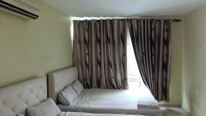 Habitación con dos camas, una ventana con cortinas y un aire acondicionado.