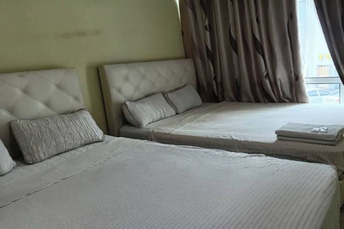 Una habitación de hotel con dos camas, cada una con cabecero y almohadas.