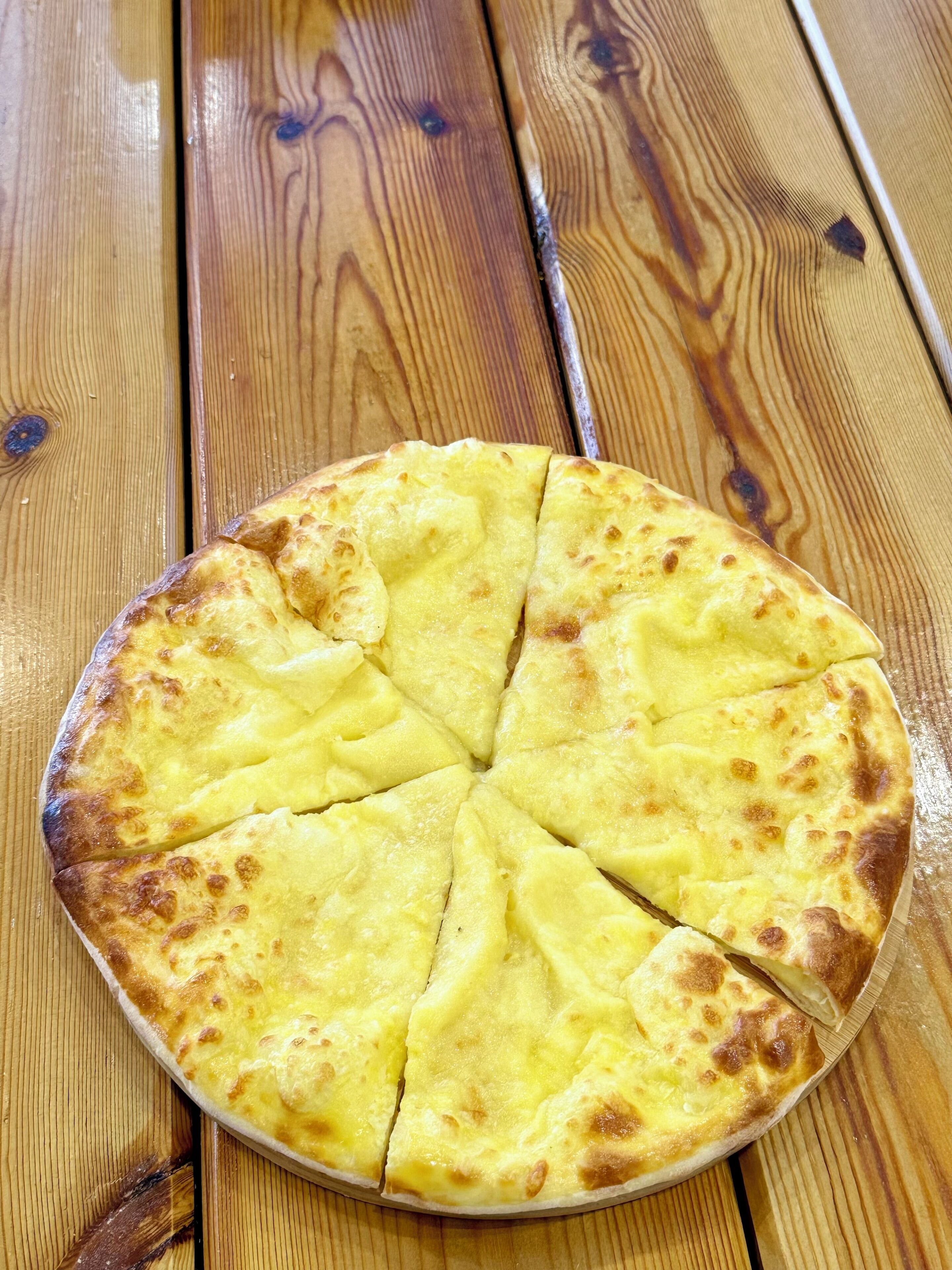 A round pizza on a wooden table.