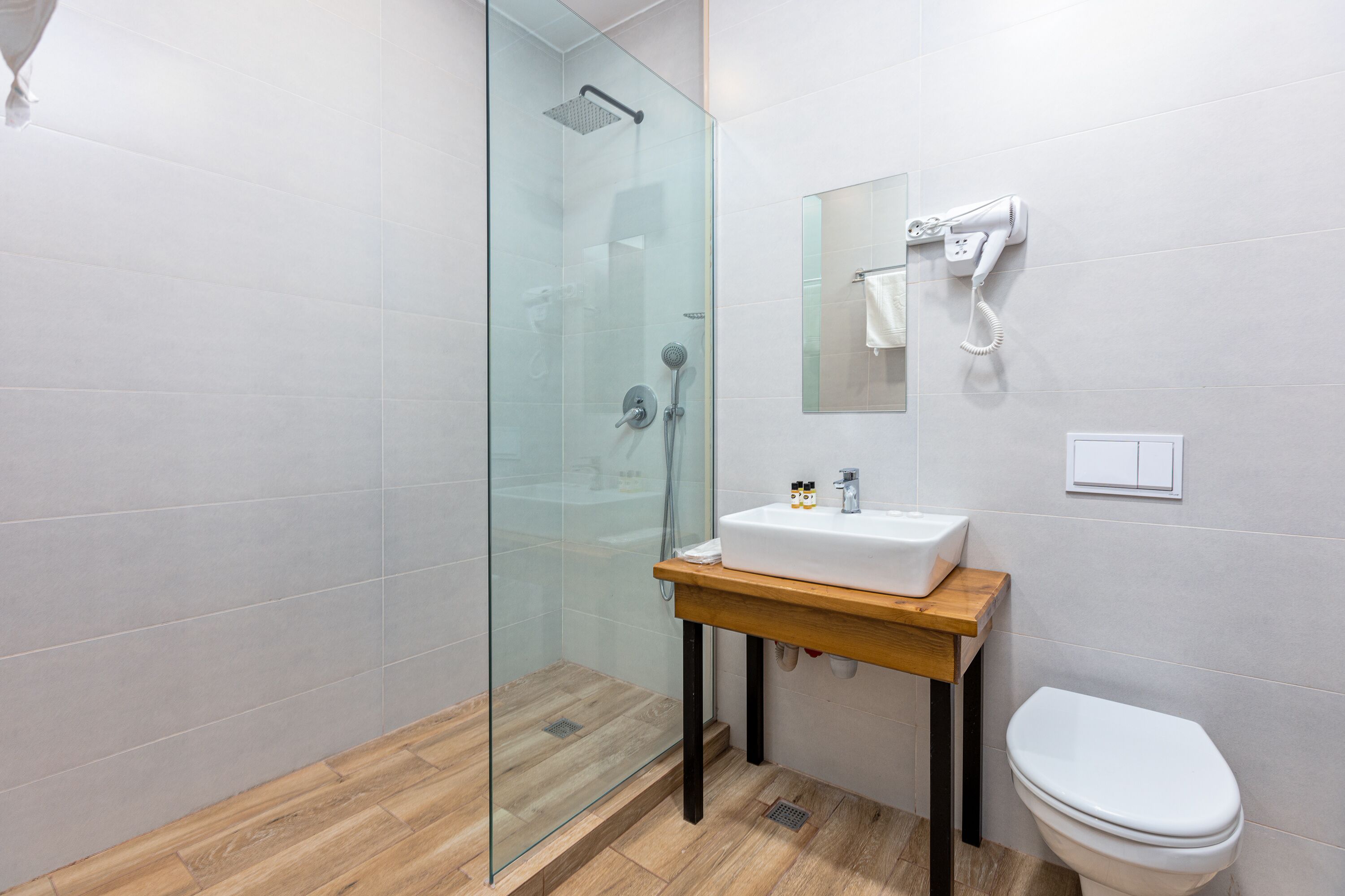 Ein modernes Badezimmer mit Duschkabine aus Glas, einem Holzwaschtisch mit Waschbecken und einer Toilette.