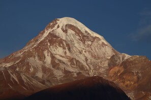 A mountain with a snow-capped peak and rugged terrain. - Mountain House Kazbegi (Kazbegi)