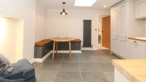 A compact kitchen with a skylight, a dining area with a bench, and a small seating area with a sofa. - Hazelrigg Cottage (Ulverston)
