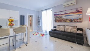 A modern living room with a sofa, a glass coffee table, and a colorful rug. - Modern apartment in Chiaia on two levels with panoramic terrace (Napoli)