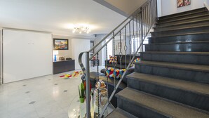 A modern living room with a staircase, a sofa with colorful cushions, a coffee table with decorative items, and a painting on the wall. - Modern apartment in Chiaia on two levels with panoramic terrace (Napoli)
