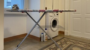 Pyykkitila, jossa on pyykkiteline, pesukone ja pesuainepulloja.