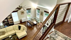 A spacious living area with a glass coffee table, a sofa, and a staircase with a wooden railing.