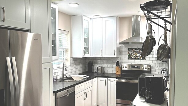 A modern kitchen with stainless steel appliances, white cabinets, and a wooden floor.