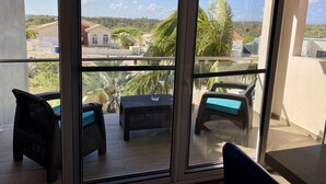 Un balcón con mobiliario de mimbre y vistas a una zona residencial.