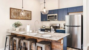 A modern kitchen with dark blue cabinets, stainless steel appliances, a marble island with bar stools, and pendant lighting. - Iron Mt Hot Spgs Condo #207 | Mtn Views | Sleeps 4 (Glenwood Springs)