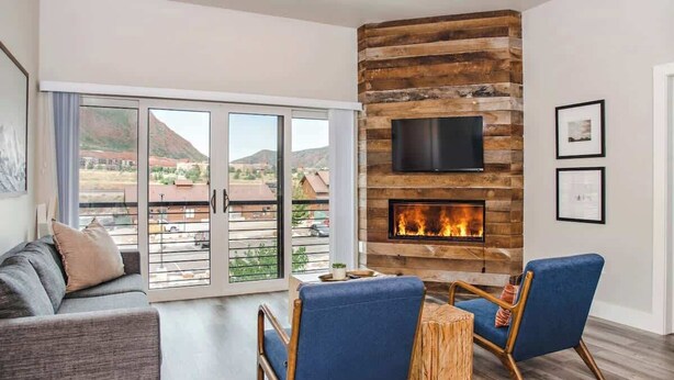 Una sala de estar con chimenea, un televisor montado en la pared y vistas al exterior.