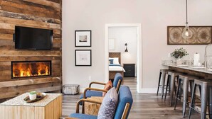 Un salón con chimenea, televisor y comedor con taburetes de bar.